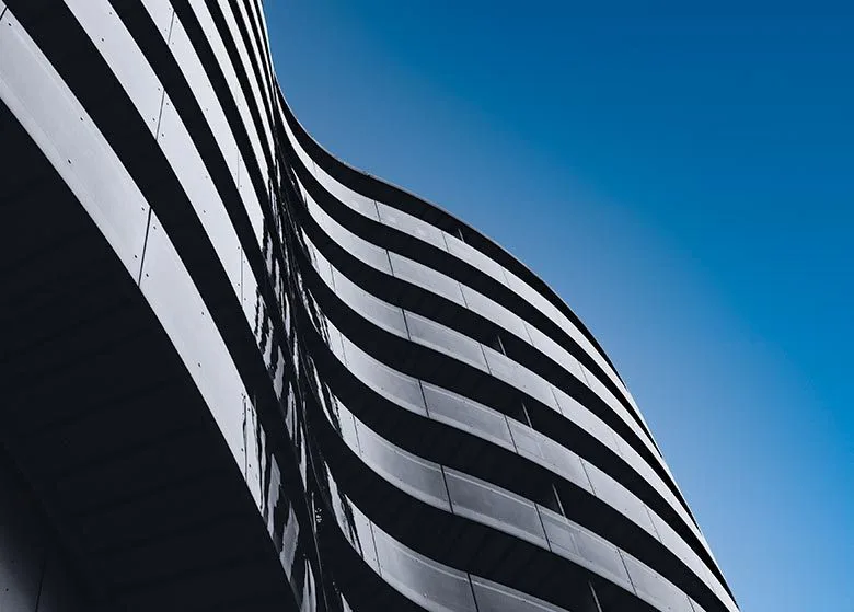 Modern curved building facade against clear blue sky.